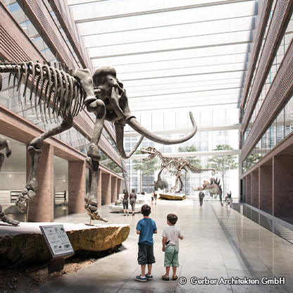 Zwei Kinder stehen in einem Museum und betrachten beeindruckende Dinosaurierskelette, die im Raum ausgestellt sind. Das Licht strömt durch eine große Glasdecke und hebt die architektonische Gestaltung des Innenraums hervor.