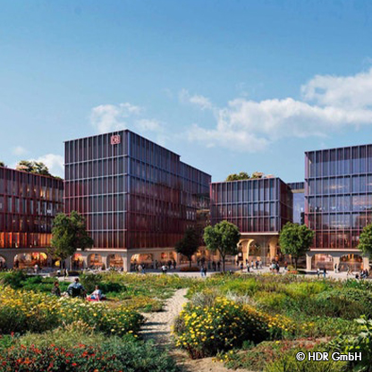 Moderne Bürogebäude mit Glasfassaden, umgeben von blühenden Gärten und grünen Flächen. Menschen sitzen und spazieren in der Umgebung. Der Himmel ist klar und sonnig, was eine einladende Atmosphäre schafft.