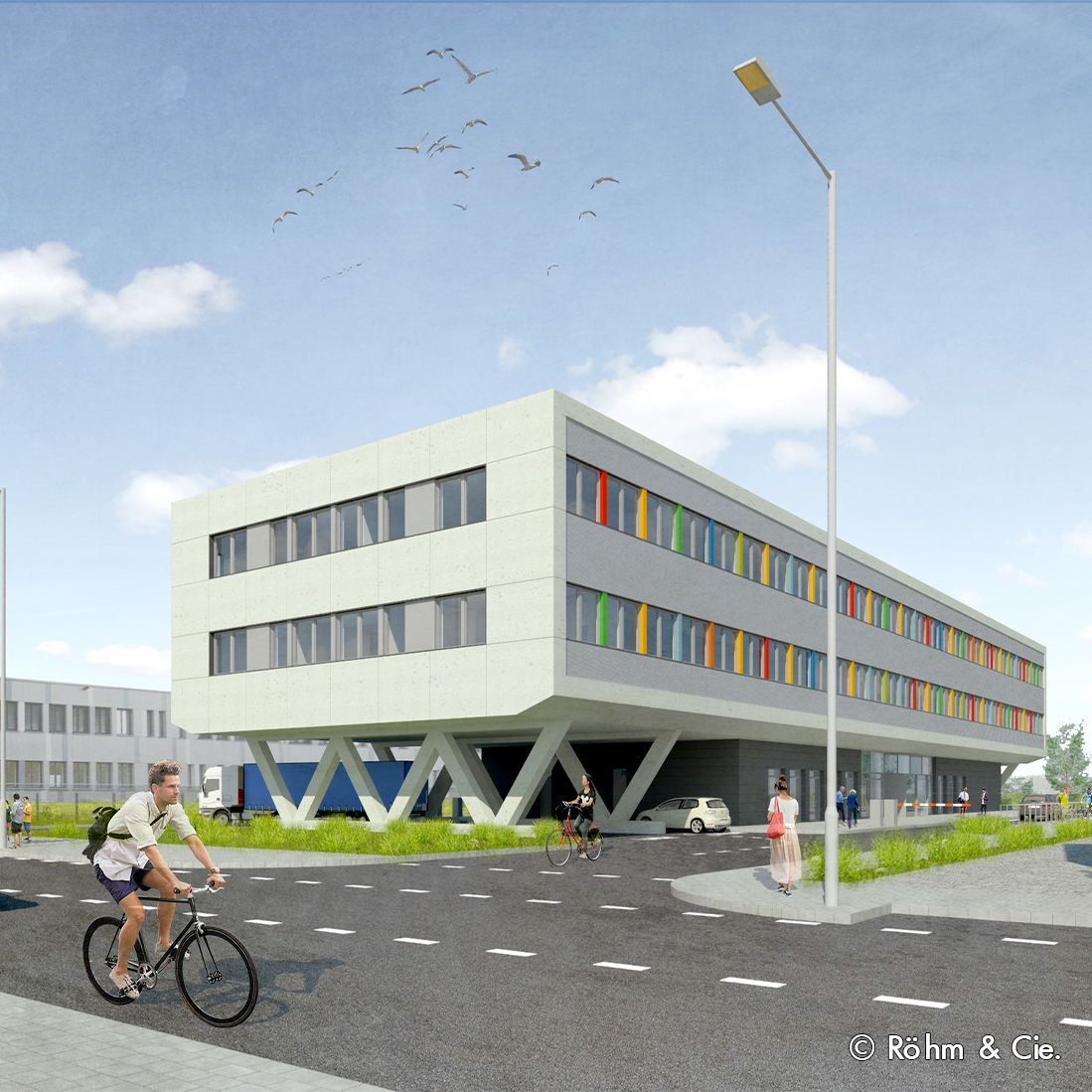 Moderne Architektur eines mehrstöckigen Gebäudes mit bunten Fenstern. Radfahrer und Fußgänger bewegen sich auf der Straße. Das Gebäude hat eine auffällige Konstruktion mit Stützen. Am Himmel sind einige Vögel zu sehen.