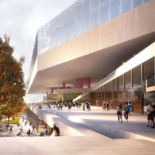 Ein modernes, architektonisches Gebäude mit mehreren Ebenen und großen Glasflächen. Menschen stehen und gehen auf den Gehwegen und im Freien. Bäume sind in der Umgebung sichtbar. Die Struktur vermittelt ein Gefühl von Offenheit und zeitgemäßem Design.