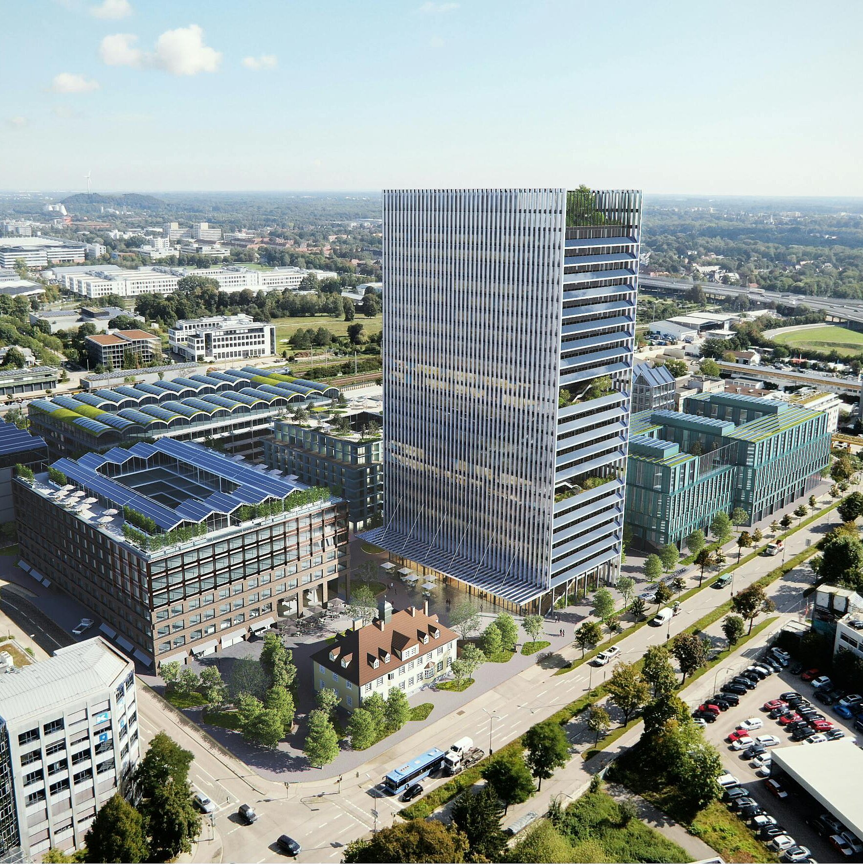 Luftaufnahme eines modernen Bürokomplexes mit mehreren Gebäuden, darunter ein hoher, gläserner Turm und niedrigere, grüne Strukturen mit Balkonen. Die Umgebung ist städtisch mit Straßen, Bäumen und einigen Parkplätzen sichtbar. Im Hintergrund sind weitere städtische Landschaften zu erkennen.