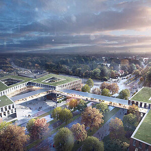 Eine Luftaufnahme eines modernen Gebäudekomplexes umgeben von Bäumen und Straßen. Die Architektur zeigt flache, grüne Dächer und eine zentrale Fußgängerbrücke, die verschiedene Bereiche miteinander verbindet. Der Himmel ist bewölkt, was eine stimmungsvolle Atmosphäre erzeugt.
