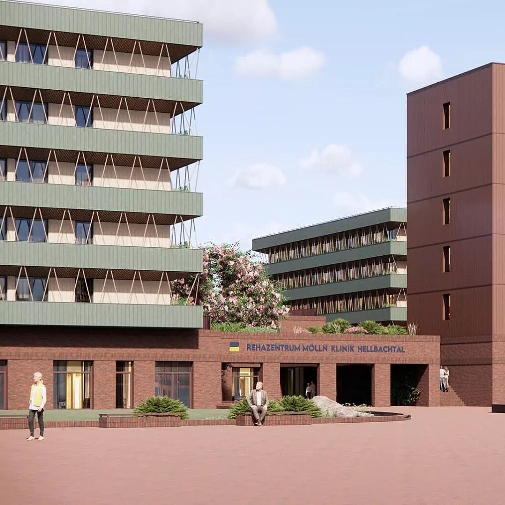 Moderne Gebäude in einem städtischen Umfeld, umgeben von Bäumen und Grünflächen. Zwei hohe Bauwerke mit unterschiedlichen Fassaden, darunter ein dreigeschossiges Gebäude. Menschen bewegen sich auf dem Platz vor den Gebäuden. Der Schriftzug über dem Eingang ist sichtbar.