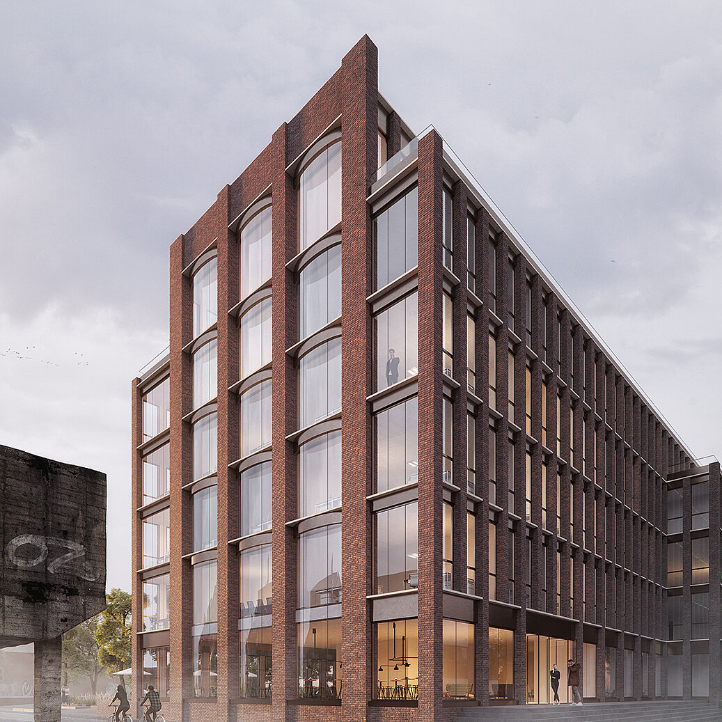 Modernes, mehrstöckiges Gebäude ausZiegel mit großen Fenstern. Die Fassade ist klar strukturiert und strahlt ein elegantes Design aus. Vor dem Gebäude sind Radfahrer sichtbar, in einer urbanen Umgebung mit Bäumen und einem leicht bewölkten Himmel.
