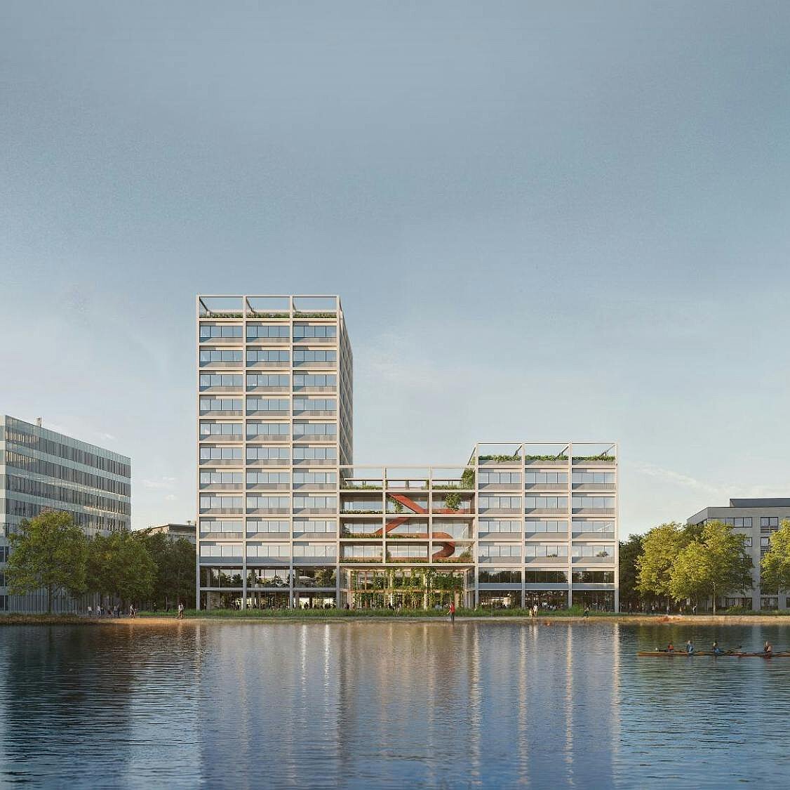 Blick auf moderne Gebäude am Ufer eines Gewässers, umgeben von Bäumen. Die Architektur ist vielfältig und zeitgenössisch, mit einer Mischung aus niedrigen und höheren Bauwerken. Der Himmel ist klar und reflektiert sich auf der Wasseroberfläche.